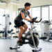 Athlète adulte de petite taille s’entraînant sur un vélo adapté dans une salle de sport lumineuse, avec les réglages ergonomiques visibles.